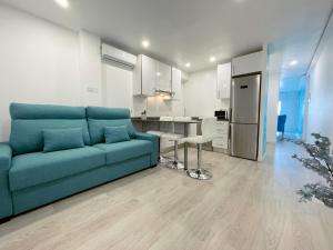 a living room with a blue couch and a kitchen at Happy LLoret in Lloret de Mar