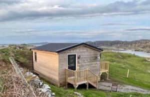 a small house on a hill with a deck at Sea View Cabin in Clashnessie