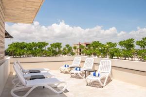 three lounge chairs on a balcony with palm trees at Boho Lofts & Studios in Playa del Carmen