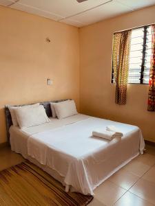 a bedroom with a bed with white sheets and a window at Wli Waterfalls Inn in Wli Afegame