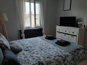 a bedroom with a bed with a tv and a dresser at Chambre double dans maison chaleureuse et familiale in Carcassonne