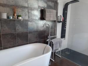 a bath tub in a bathroom with a tiled wall at Maison chaleureuse et familiale in Carcassonne