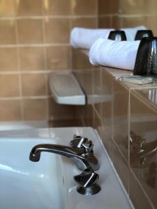 La salle de bains est pourvue d'un lavabo, d'un sèche-cheveux et de serviettes sur une étagère. dans l'établissement Grand hôtel de l'Europe, à Vals-les-Bains