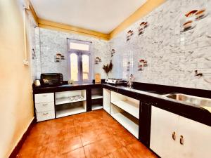 a kitchen with white cabinets and a stone wall at Kalimpong Sunrise-Inn Homestay in Kalimpong