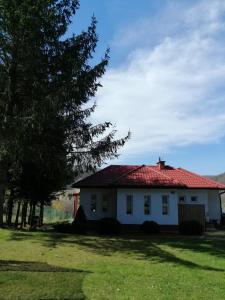una casa blanca con techo rojo en un patio en Pensjonat na Wzgórzu en Solina