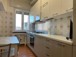 una cocina con armarios blancos y una mesa. en Apartment Station Sesto - Affitti Brevi Italia, en Sesto San Giovanni