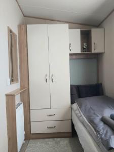 a bedroom with a white cabinet next to a bed at Vista Al Mar, Seaview Caravan Park, Whitstable in Kent