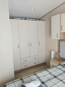 a bedroom with white cabinets and a bed at Vista Al Mar, Seaview Caravan Park, Whitstable in Kent