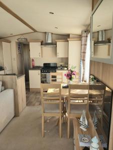 a kitchen and living room with a table and chairs at Vista Al Mar, Seaview Caravan Park, Whitstable in Kent