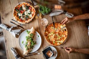 dos pizzas en una mesa de madera con platos de comida en Hotel Löwenhof, en Bresanona