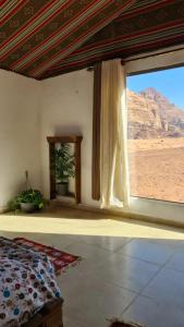 a bedroom with a large window with a view of the desert at wadi rum Martian camp in Wadi Rum
