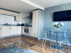 a kitchen with a glass table with chairs and a tv at Penthouse Birmingham City View in Birmingham