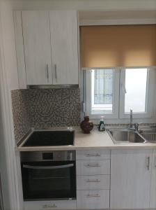 a kitchen with white cabinets and a stove and a sink at Villa Christos Family Bungalow Pachis Beach in Pachis