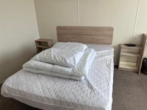 a bedroom with a bed with white sheets and pillows at PG173 Golden Palm Resort 6 Berth Caravan With Decking in Chapel Saint Leonards