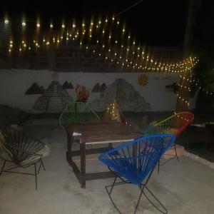 une table et des chaises en bois devant un mur éclairé dans l'établissement Hostal Casa Amarilla Tecámac, à Santa Cruz Tecamac