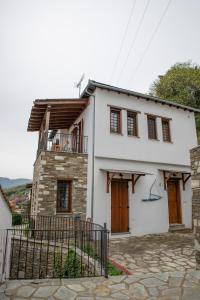 a white house with wooden doors and a balcony at Notas Pelion Seaview Villa in Zagora