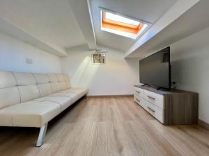 a living room with a white couch and a flat screen tv at Amori di Sicilia in Cefalù