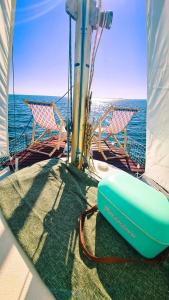 um barco com duas cadeiras e uma prancha de surf no deque em Sirius - Boat House em Olhão