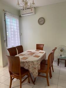 a dining room table with chairs and a clock on the wall at JML Family Homestay ~ Entire Residential Home in Kota Kinabalu