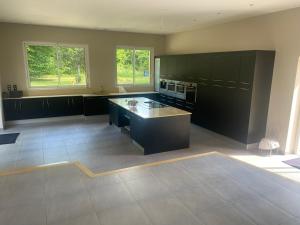 a large kitchen with black cabinets and a counter at Villa & Spa Piscine chauffée 5 minutes de Sarlat in Proissans