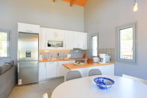 a kitchen with white cabinets and a table with a bowl on it at Villa Christina in Pouládes
