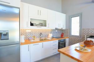 a kitchen with white cabinets and a refrigerator at Villa Christina in Pouládes