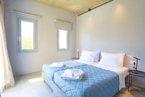 a bedroom with a blue bed with towels on it at Villa Christina in Pouládes +17 photos