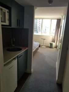 una cocina con fregadero y una cama en una habitación en Chatswood Hotel en Sídney