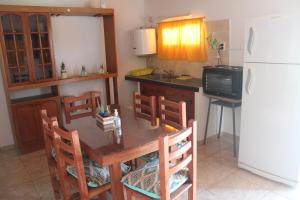 cocina con mesa, sillas y nevera en Cabañas Doña Antonia en San Juan