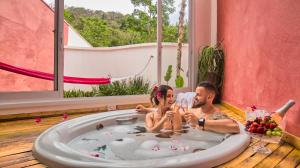 Ein Mann und eine Frau sitzen in einer Badewanne in der Unterkunft Hotel Boutique Frangipani in Brotas