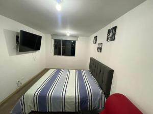 ein Schlafzimmer mit einem Bett und einem TV. in der Unterkunft Apartamento nuevo en Tunja in Tunja