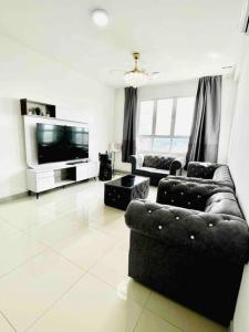 Una sala de estar con un sofá y un televisor. en KT CITY HOMESTAY WITH 4 Bedrooms and POOL, en Kuala Terengganu