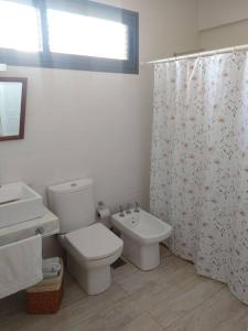 a bathroom with a toilet and a sink and a shower curtain at Madame Chacras in Chacras de Coria