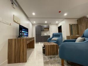 Sala de estar con 2 sillas azules y TV en روشن الماسي للشقق المخدومة en Yanbu