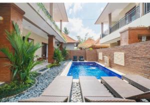 a swimming pool with chaise lounges next to a building at Komala Homestay in Canggu