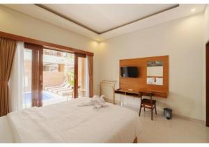 a bedroom with a bed and a desk and a television at Komala Homestay in Canggu
