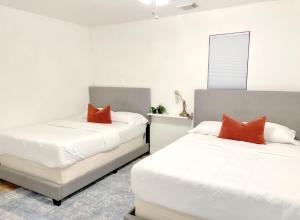 2 camas en una habitación con almohadas blancas y naranjas en Boho Chic en Humble