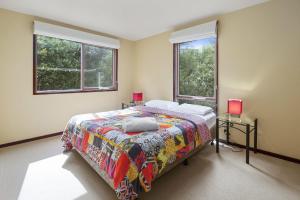 a bedroom with a bed and two windows at Swingbridge in Lorne