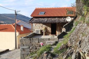 uma pequena casa de pedra com um telhado vermelho em Comfortable rural cottage in ancient village in the Douro region em Viseu