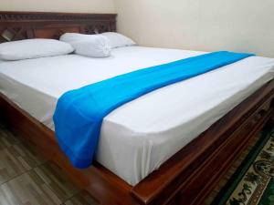 a bed with a blue blanket on top of it at Shinta Syariah Homestay Dieng RedPartner in Dieng