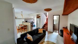 uma sala de estar com um sofá preto e uma cozinha em Chalé Fantástico - Centro de Pipa - Resort Pipa em Pipa