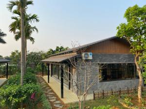 una casa con la facciata nera e una palma di MOMIZI INN a Ba Vì