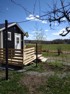 une petite cabine avec une terrasse couverte dans un champ dans l'établissement Countrycabin Bergslagen stuga, à Ramsberg