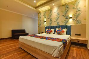 a bedroom with a large bed and a chair at FabHotel Clive Regency Lovelock in kolkata