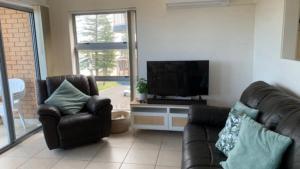 a living room with two leather chairs and a flat screen tv at #3 Moondara, Bulcock Beach Esplanade W - View in Caloundra
