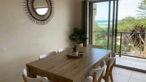 a dining room with a table and chairs and a mirror at #3 Moondara, Bulcock Beach Esplanade W - View in Caloundra