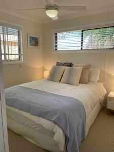 a bedroom with a large bed and two windows at Patonga Street Retreat in Patonga