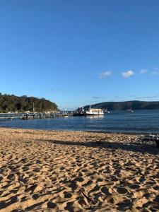 einen Sandstrand neben dem Wasser mit einem Pier in der Unterkunft Patonga Street Retreat in Patonga + 18 Fotos