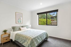a white bedroom with a bed and a window at Chatleys in Aireys Inlet
