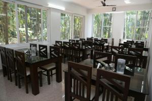 a dining room with tables and chairs and windows at Hosamane Farm Inn in Sringeri